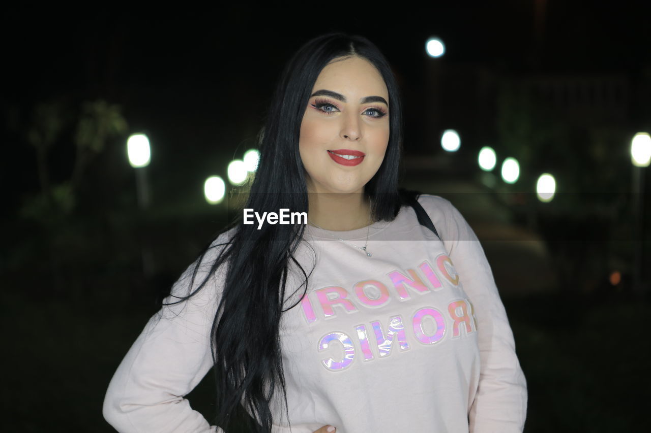 Portrait of beautiful woman standing outdoors at night