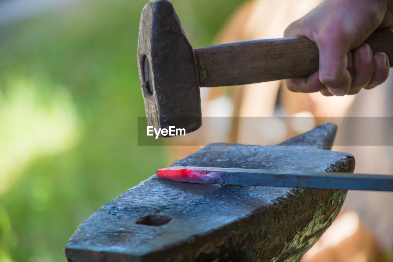 Cropped hand hammering metal on anvil