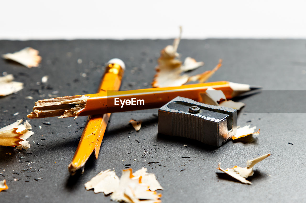 Broken pencil with metal sharpener and shavings on black background. horizontal image.