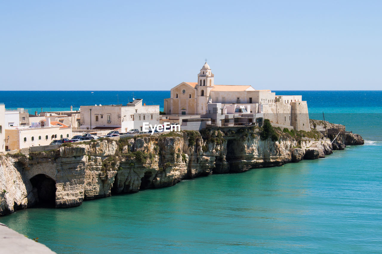 Panoramic shot of sea by buildings against clear sky