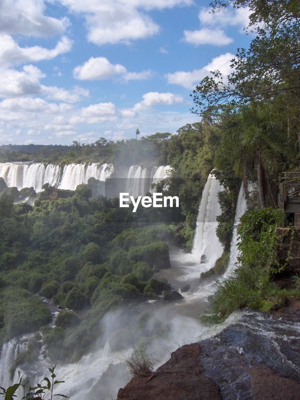 Scenic view of waterfall against cloudy sky