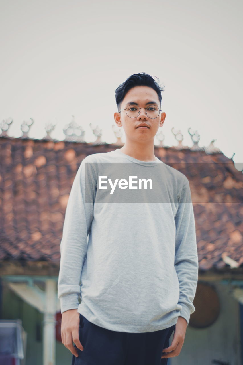 Portrait of young man standing against clear sky