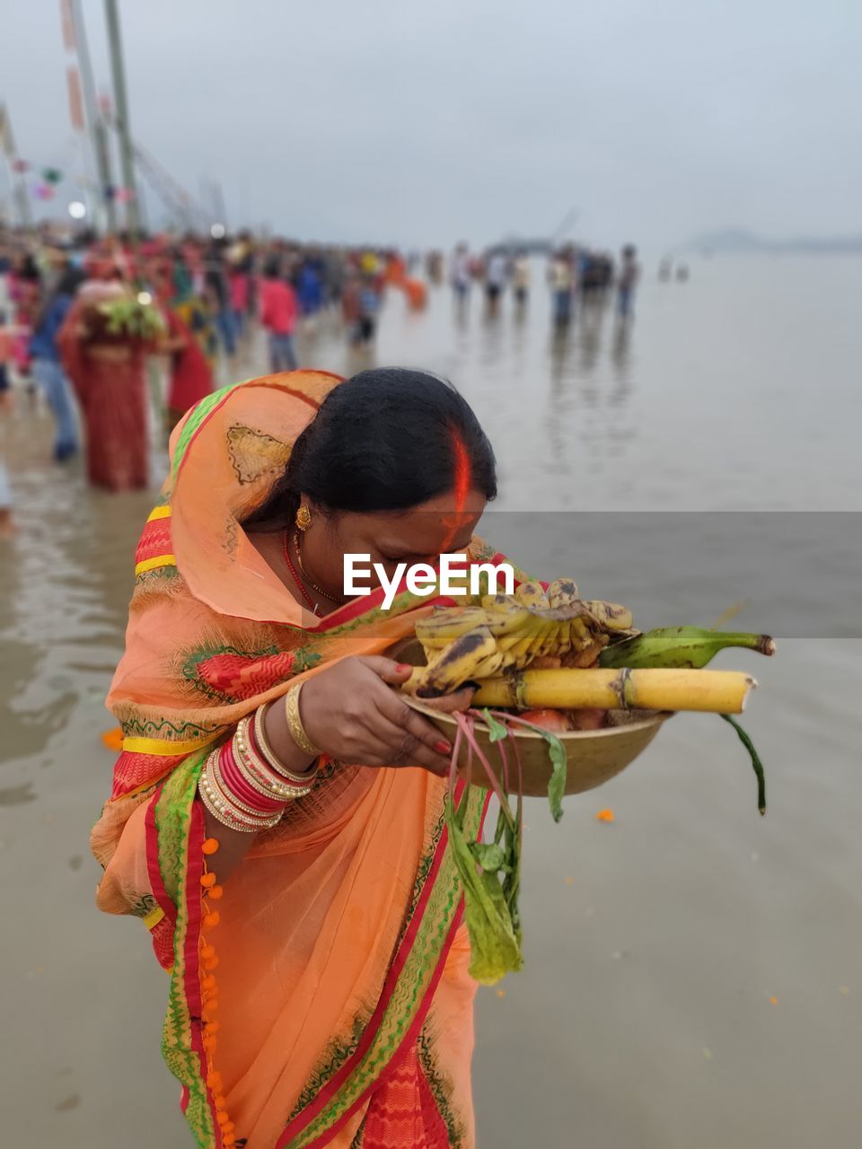 On the eve of chath puja she is praying to the rising sun  with fruits, veggies and homemade sweet.