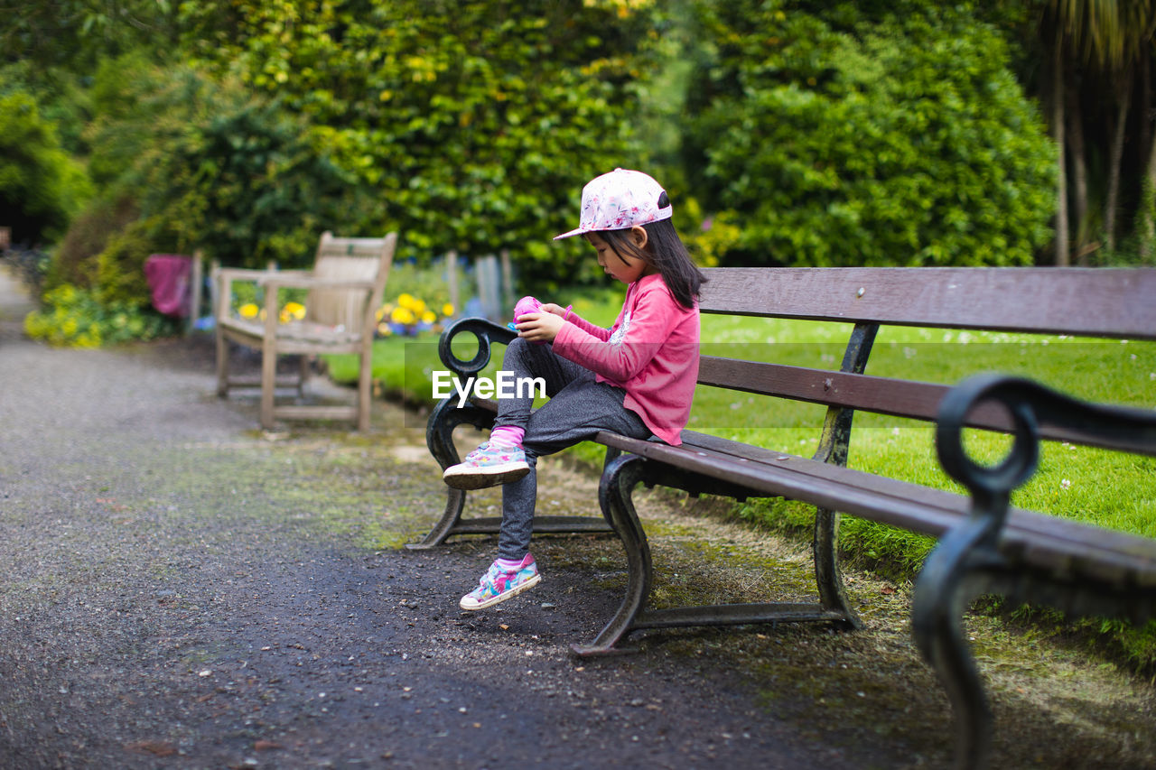 Young girl sitting on chair and watching her camera in summer garden