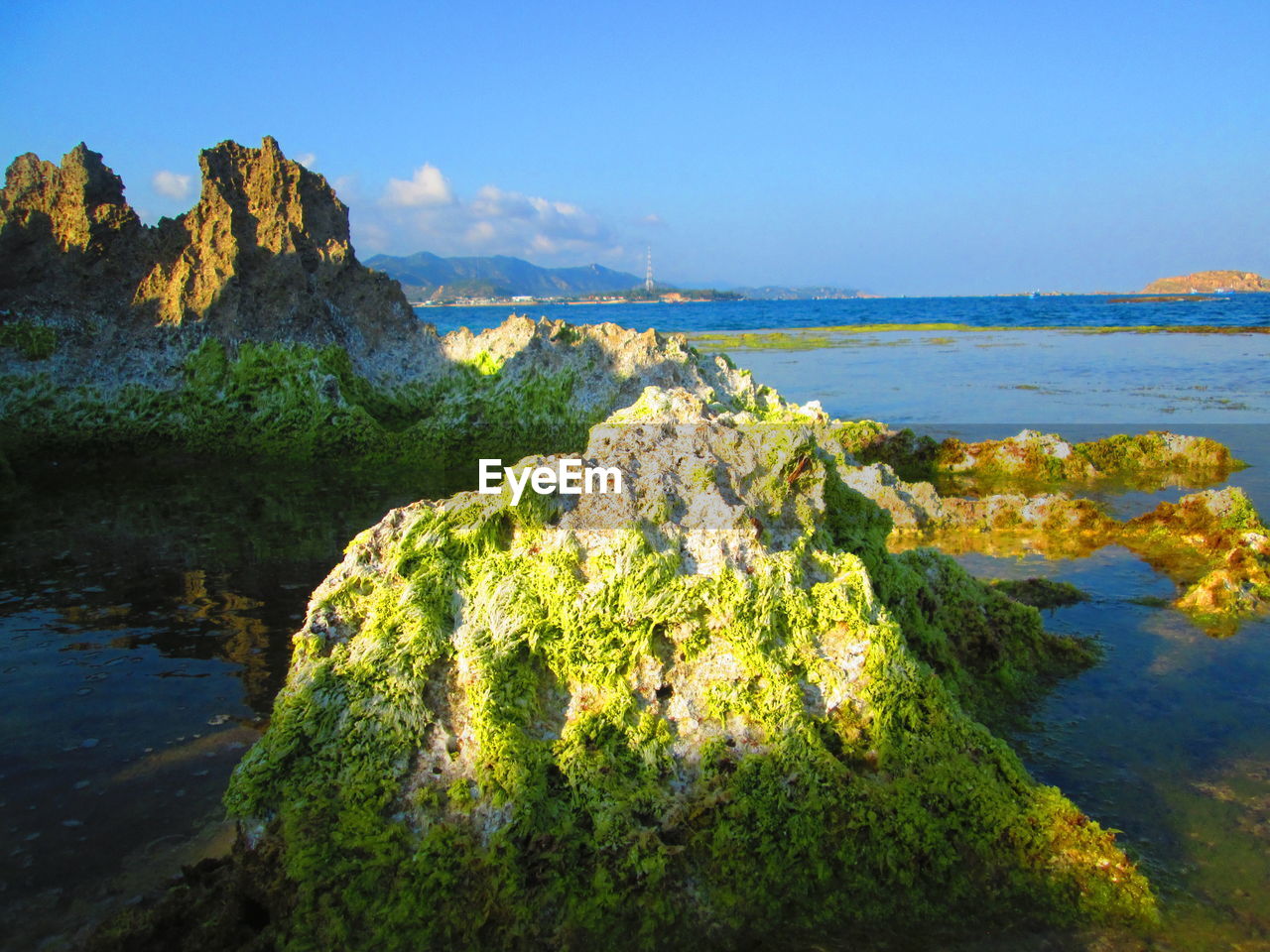 Scenic view of rocks by sea against sky