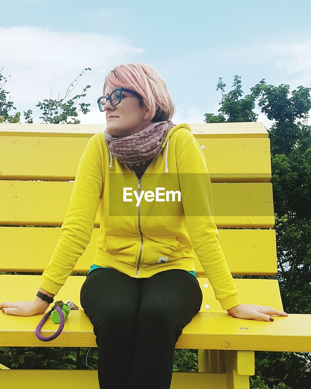 Woman sitting against yellow bench