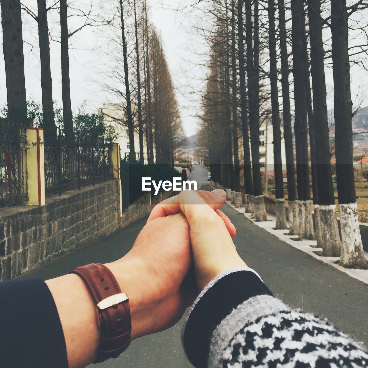 Cropped image of couple holding hands on road