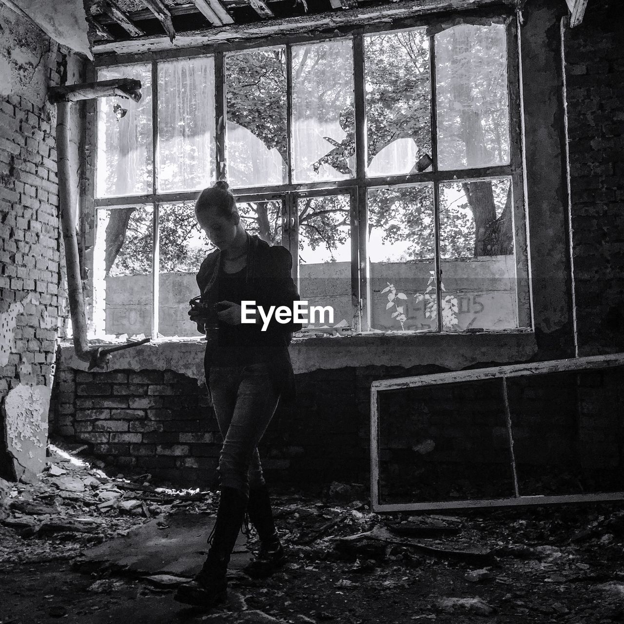 Full length of woman walking with camera in abandoned building