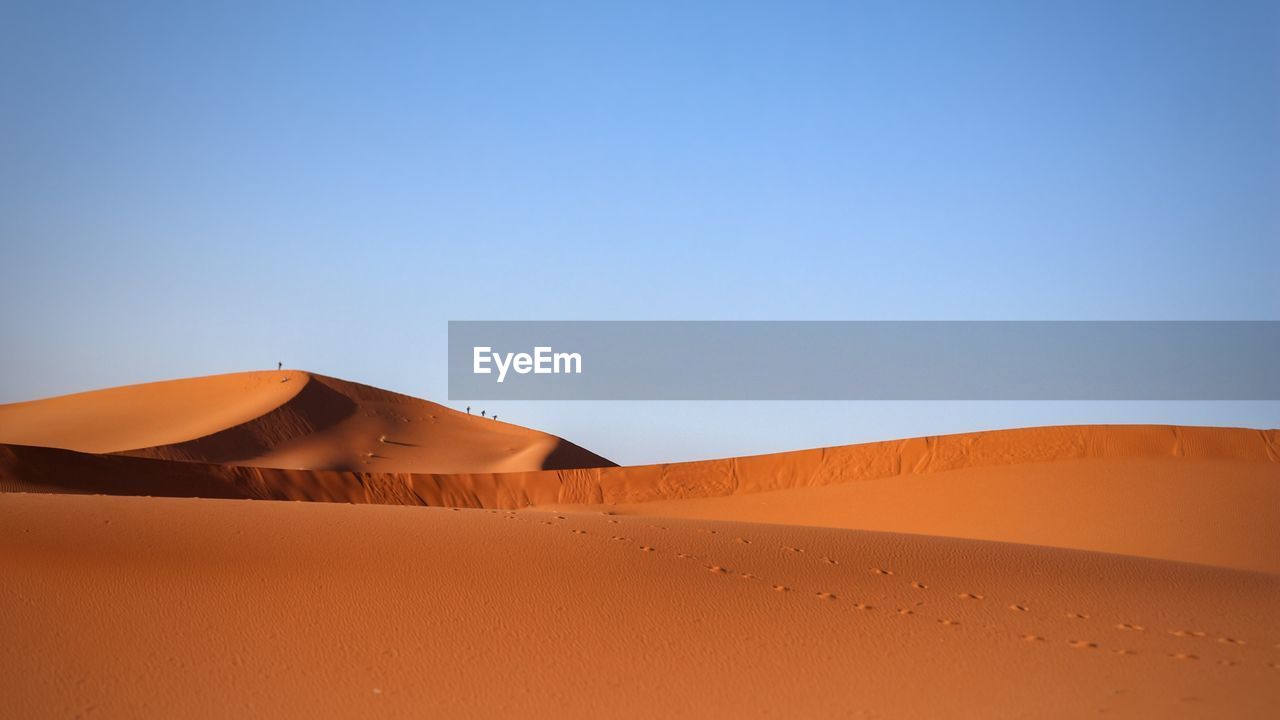 Sand dunes in desert against clear blue sky