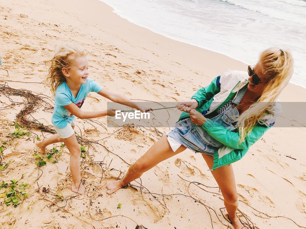 Tilt image of playful mother and daughter on beach