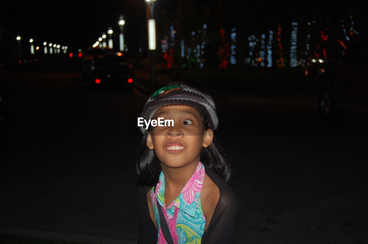 Playful girl making face on street in city at night
