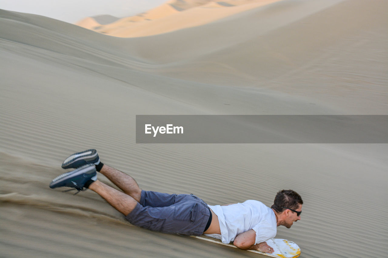 Full length of man sandboarding in desert