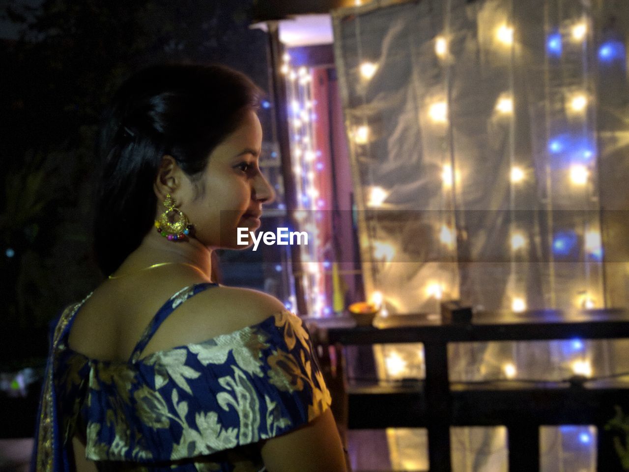 PORTRAIT OF A YOUNG WOMAN LOOKING AWAY AT ILLUMINATED NIGHT