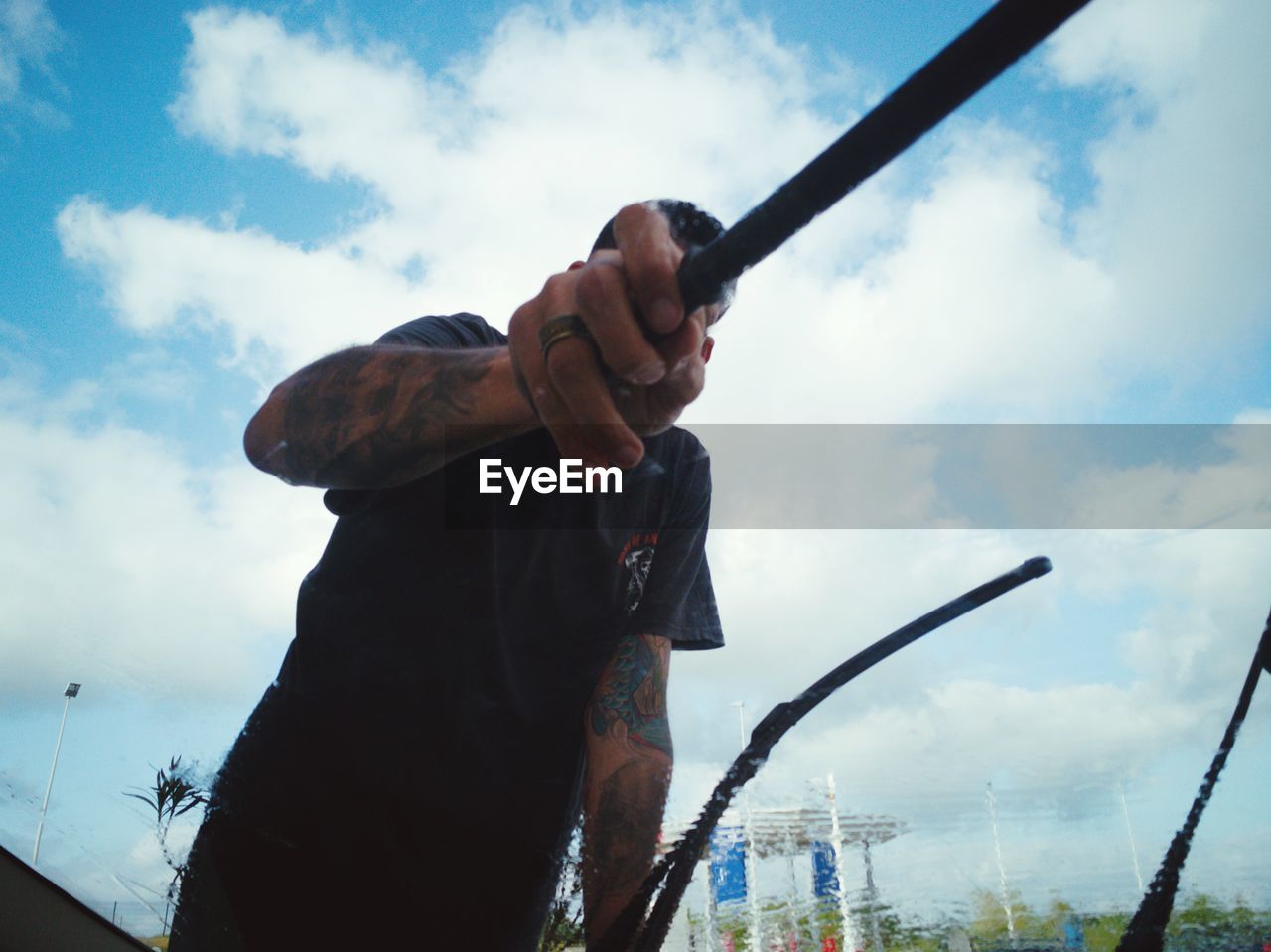 MAN HOLDING CAMERA AGAINST SKY IN BACKGROUND