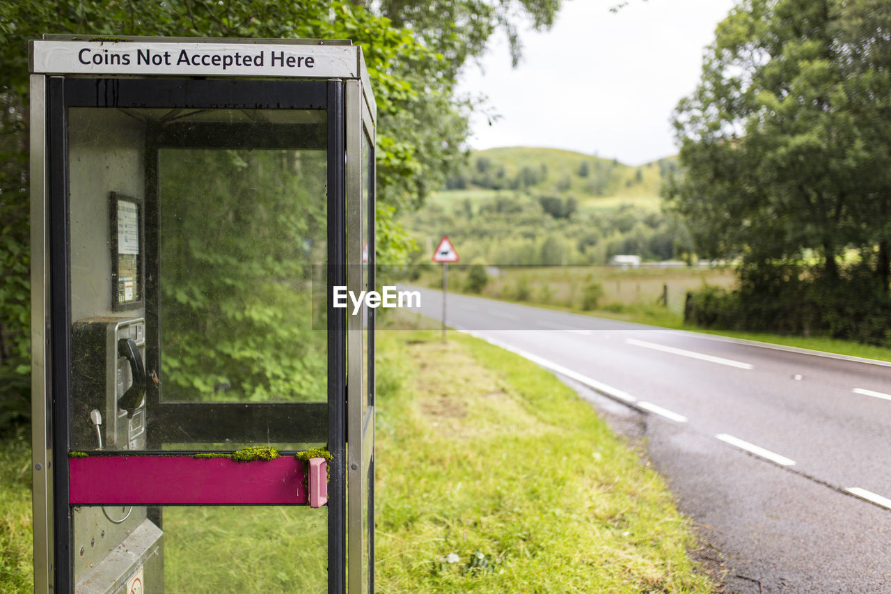 Telephone booth on field by road