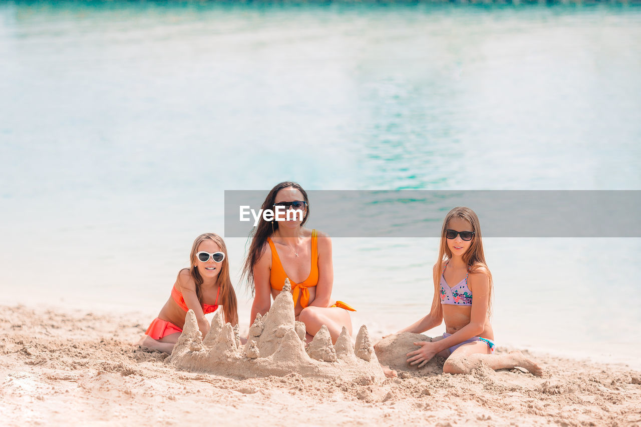 Portrait of mother and daughters making sandcastle at beach