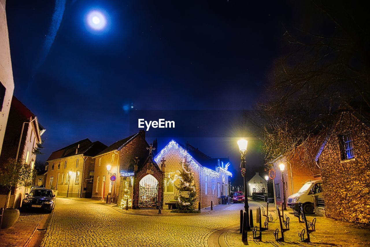 Historic chapel by illuminated street against sky at night during christmas