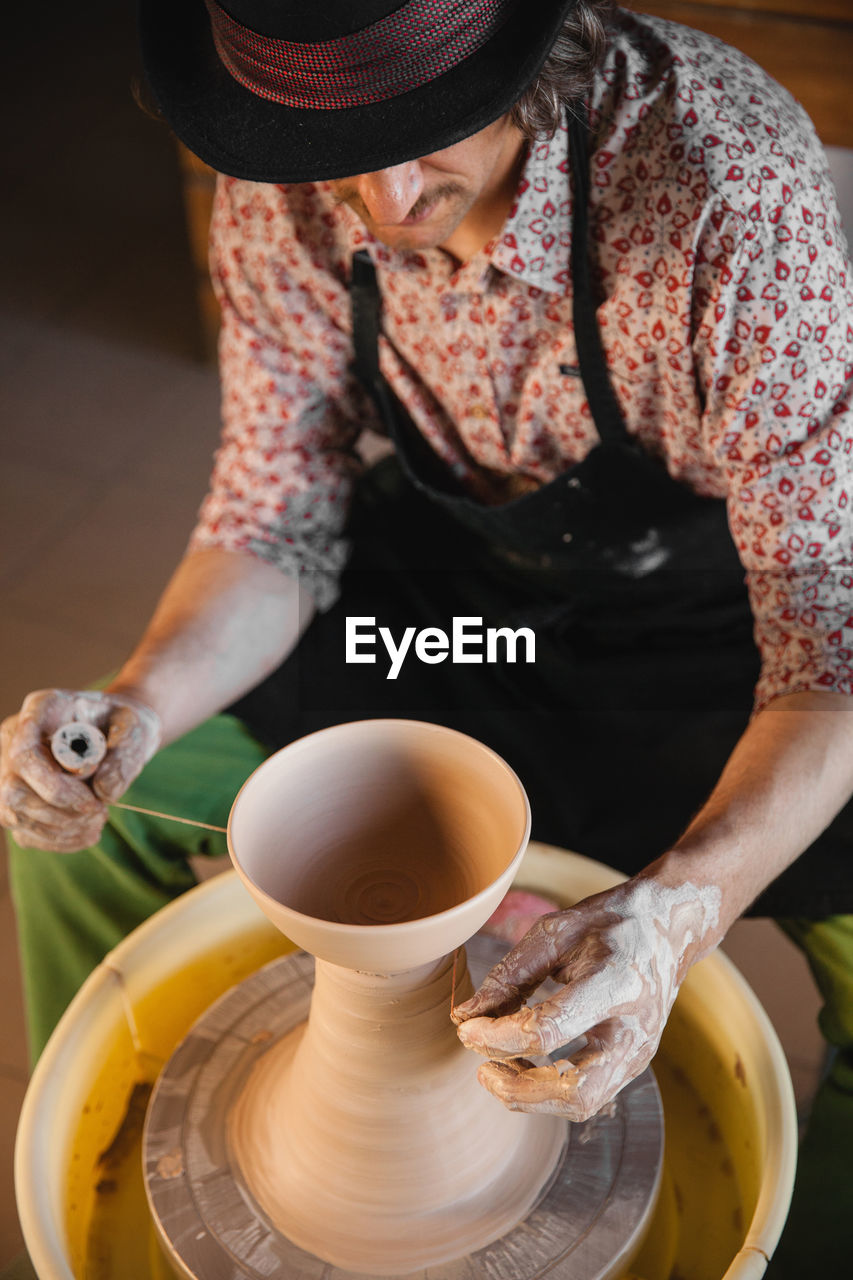 potter's wheel, adult, art, one person, occupation, pottery, craft, indoors, working, food and drink, skill, women, holding, ceramic, making, creativity, clay, business, lifestyles, small business, craftsperson, expertise, pitcher - jug, young adult, person, front view, apron, food