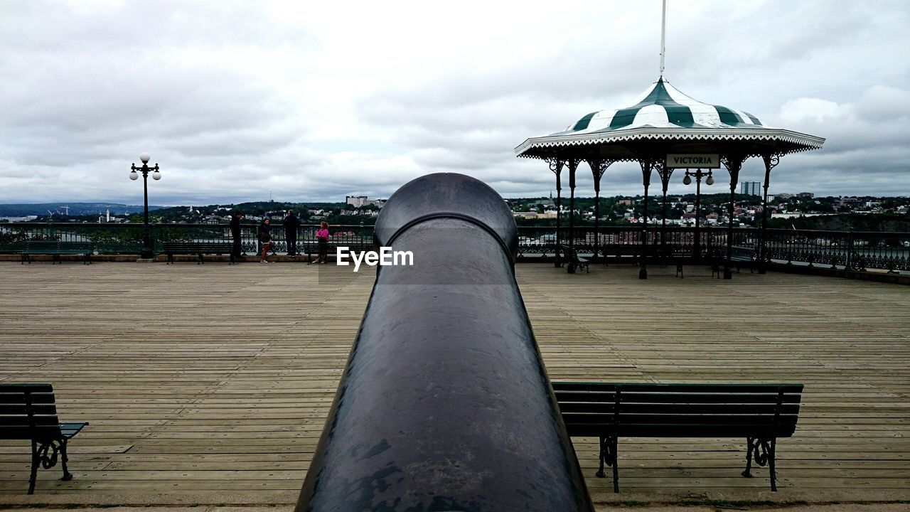 EMPTY BENCHES AGAINST CLOUDY SKY