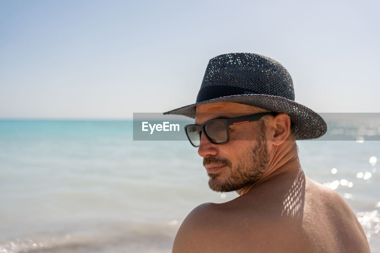 Man in summer hat and sunglasses on sea beach