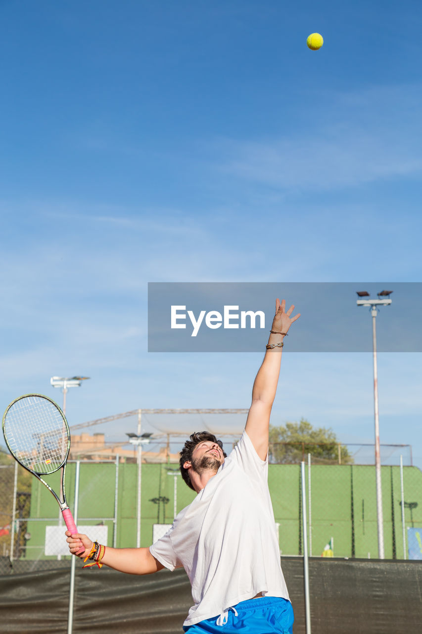 Young man playing tennis against sky