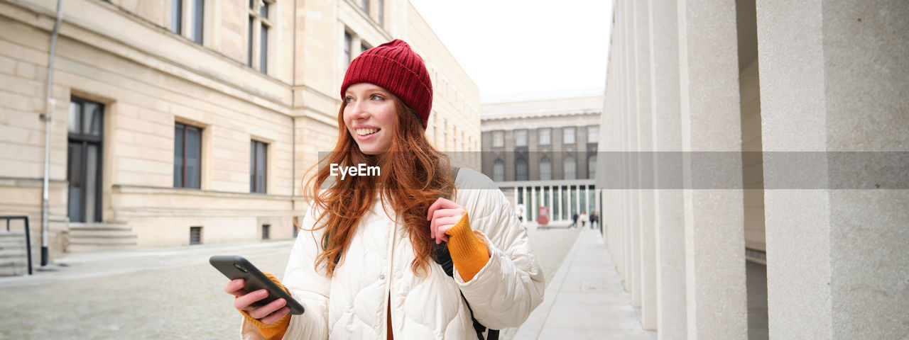 portrait of young woman standing against building