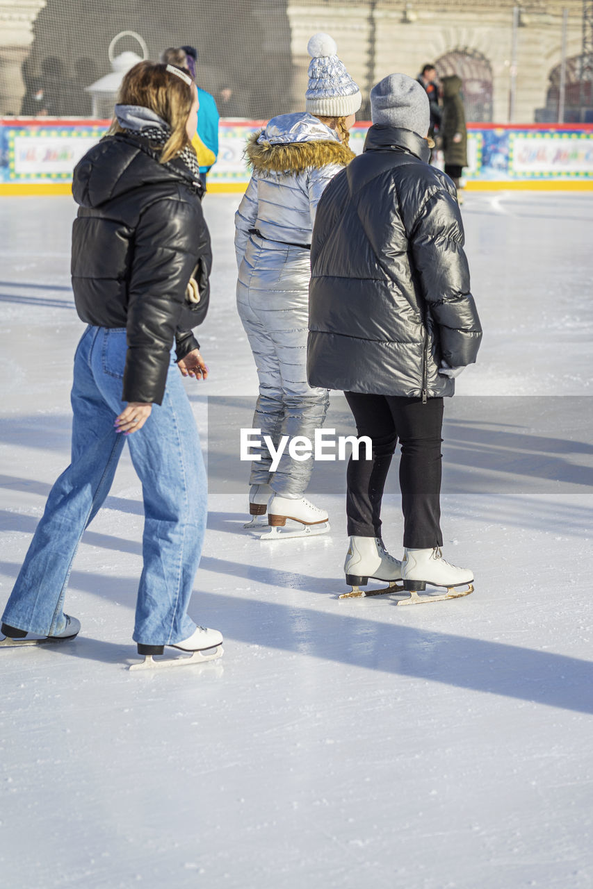 ice skating, winter, winter sports, cold temperature, full length, ice rink, ice, adult, snow, architecture, group of people, sports, men, women, rear view, city, clothing, togetherness, day, skating, leisure activity, warm clothing, lifestyles, ice skate, motion, footwear, jeans