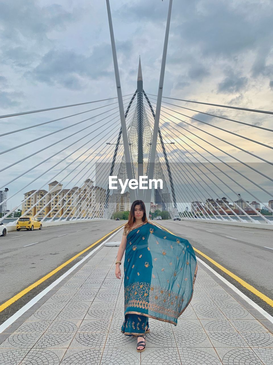 Portrait of woman in sari standing on bridge against sky