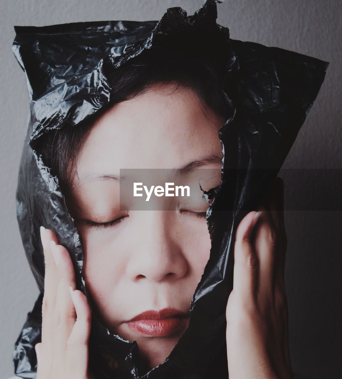 Close-up of woman with eyes closed covered in plastic
