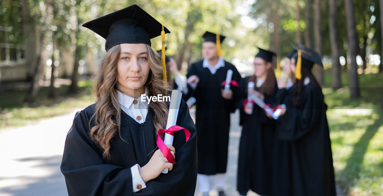 portrait of woman wearing graduation gown standing in city