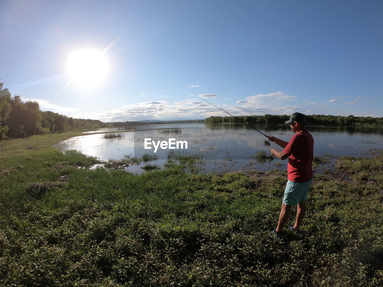 FULL LENGTH OF MAN STANDING ON LAKE AGAINST SKY