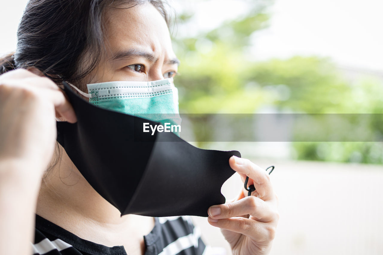 woman is wearing a second mask,people putting double or a medical protective mask under a cloth mask