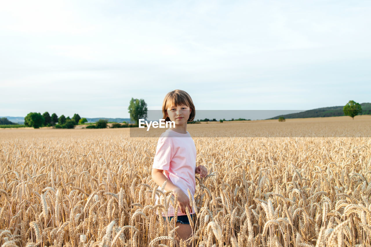 Portrait of a teenage girl in a field of ears of rye at sunset. child enjoys nature person