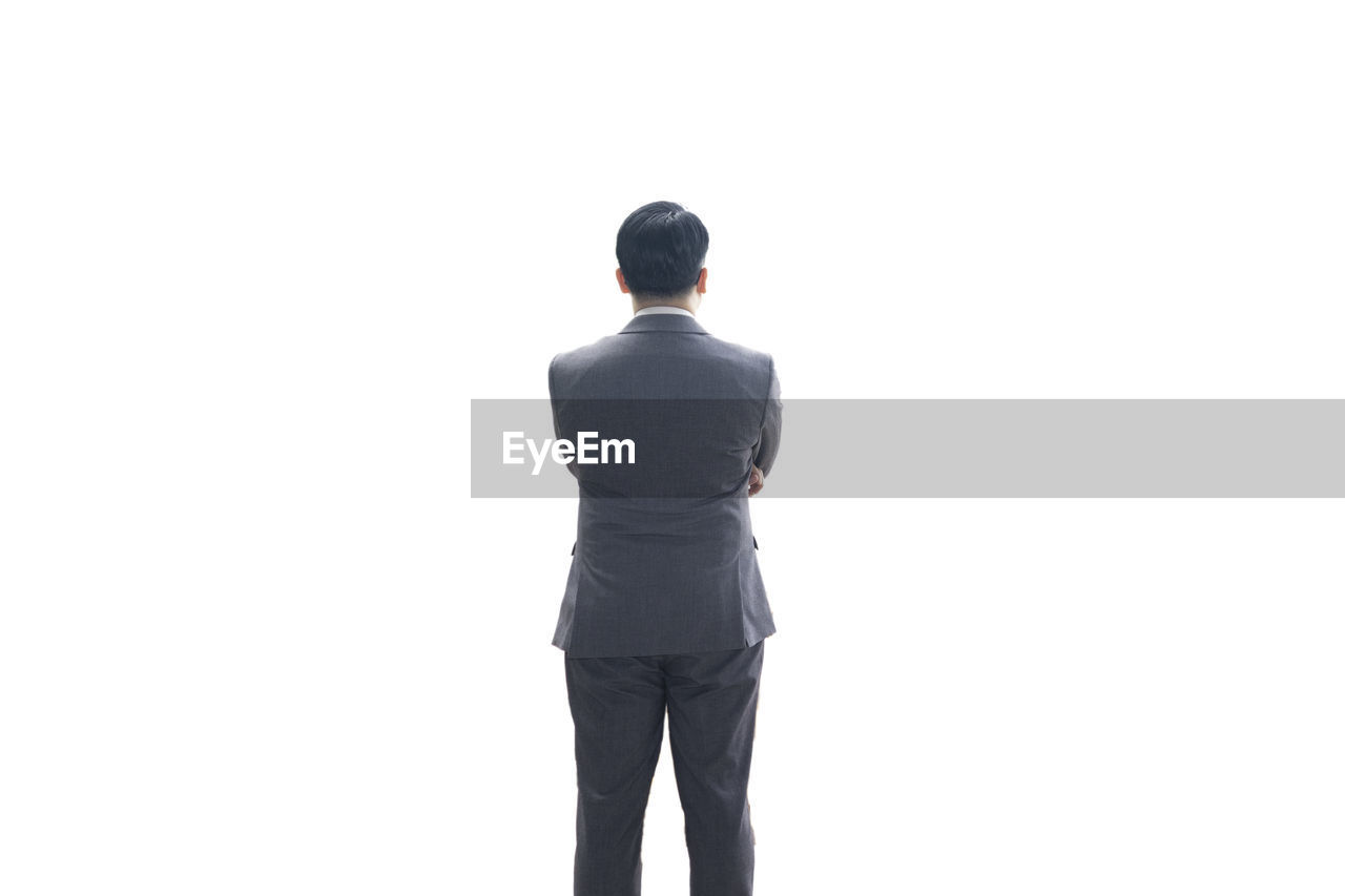 REAR VIEW OF MAN STANDING ON WHITE BACKGROUND