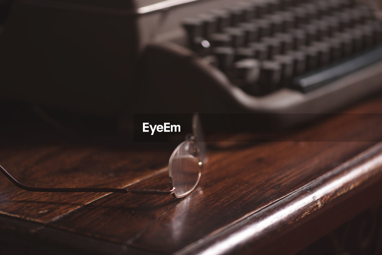Close-up of eyeglasses by typewriter on table