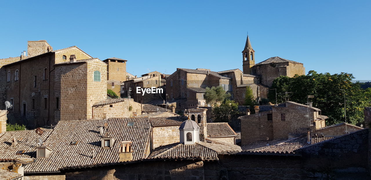 Buildings in city against clear blue sky