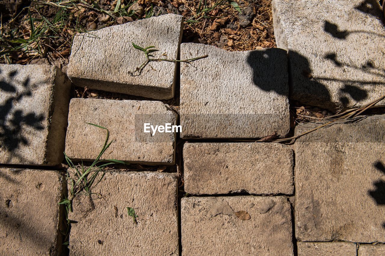 HIGH ANGLE VIEW OF STONE WALL WITH SHADOW ON THE GROUND