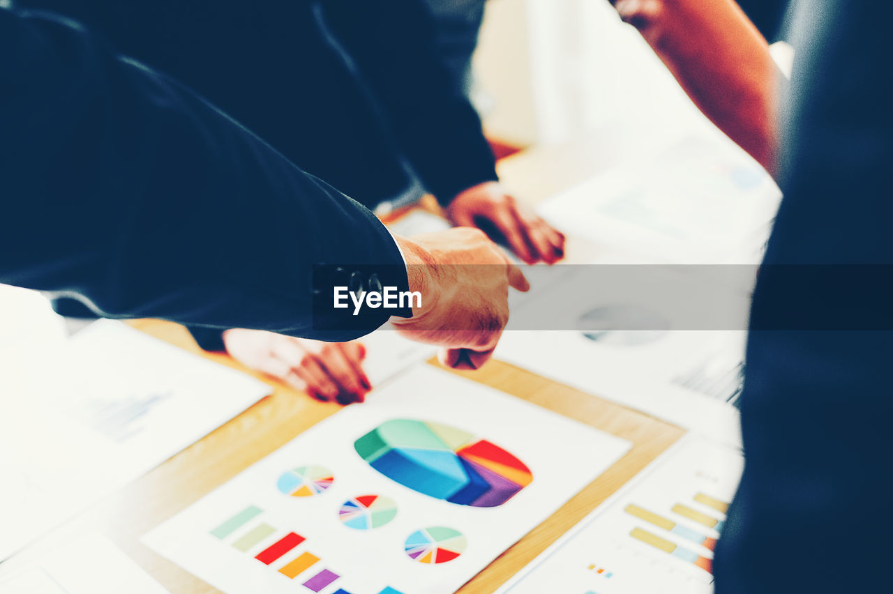 Midsection of business people working over graph on table at office