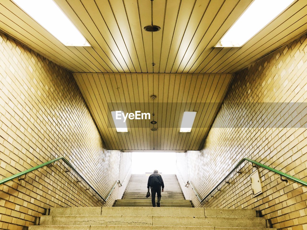 Rear view of man walking on illuminated steps at subway station