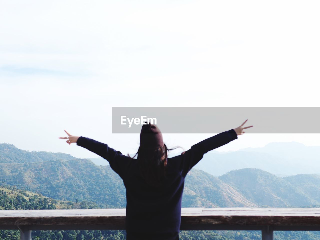 Rear view of woman with arms outstretched standing on mountain