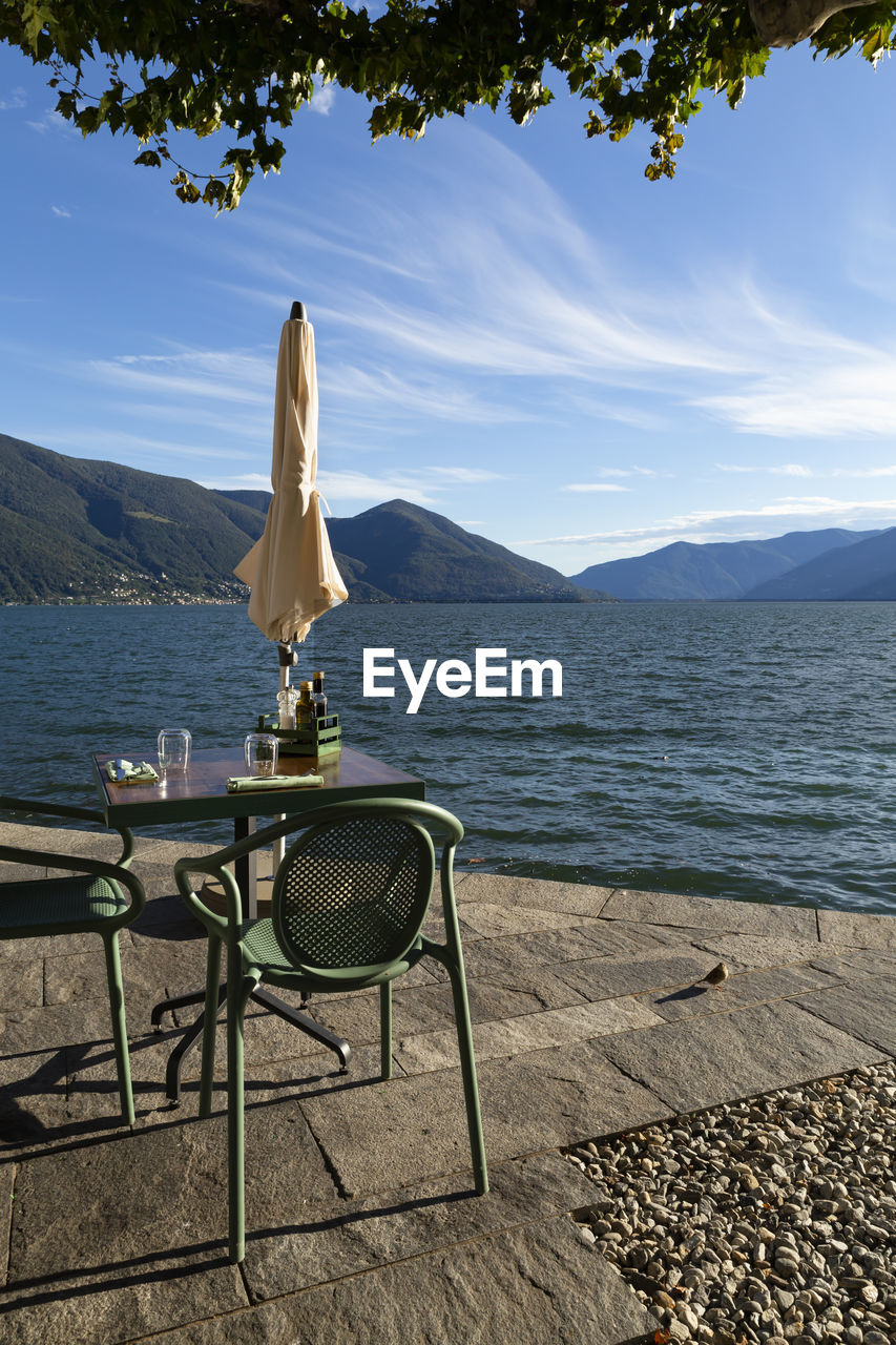 Switzerland, ascona, 1 sept 20. idyllic place with table and chairs on the border of lago maggiore