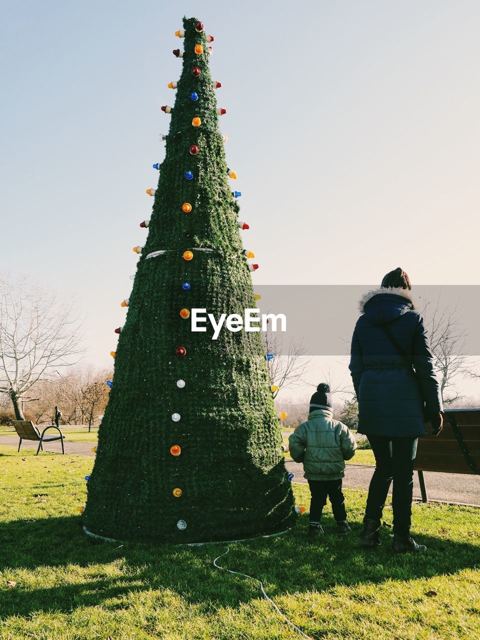 Family standing by christmas tree against clear sky