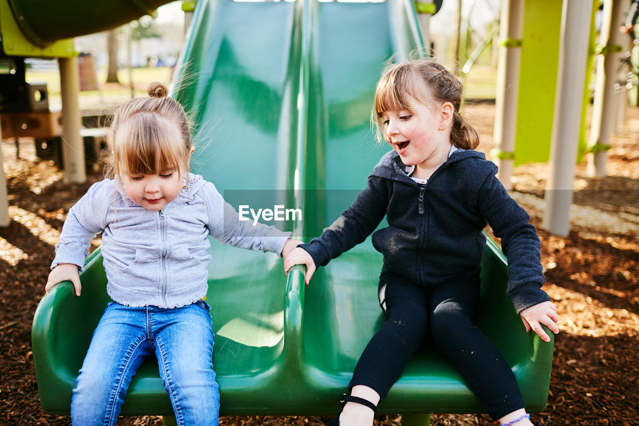 Siblings sitting on swing at park