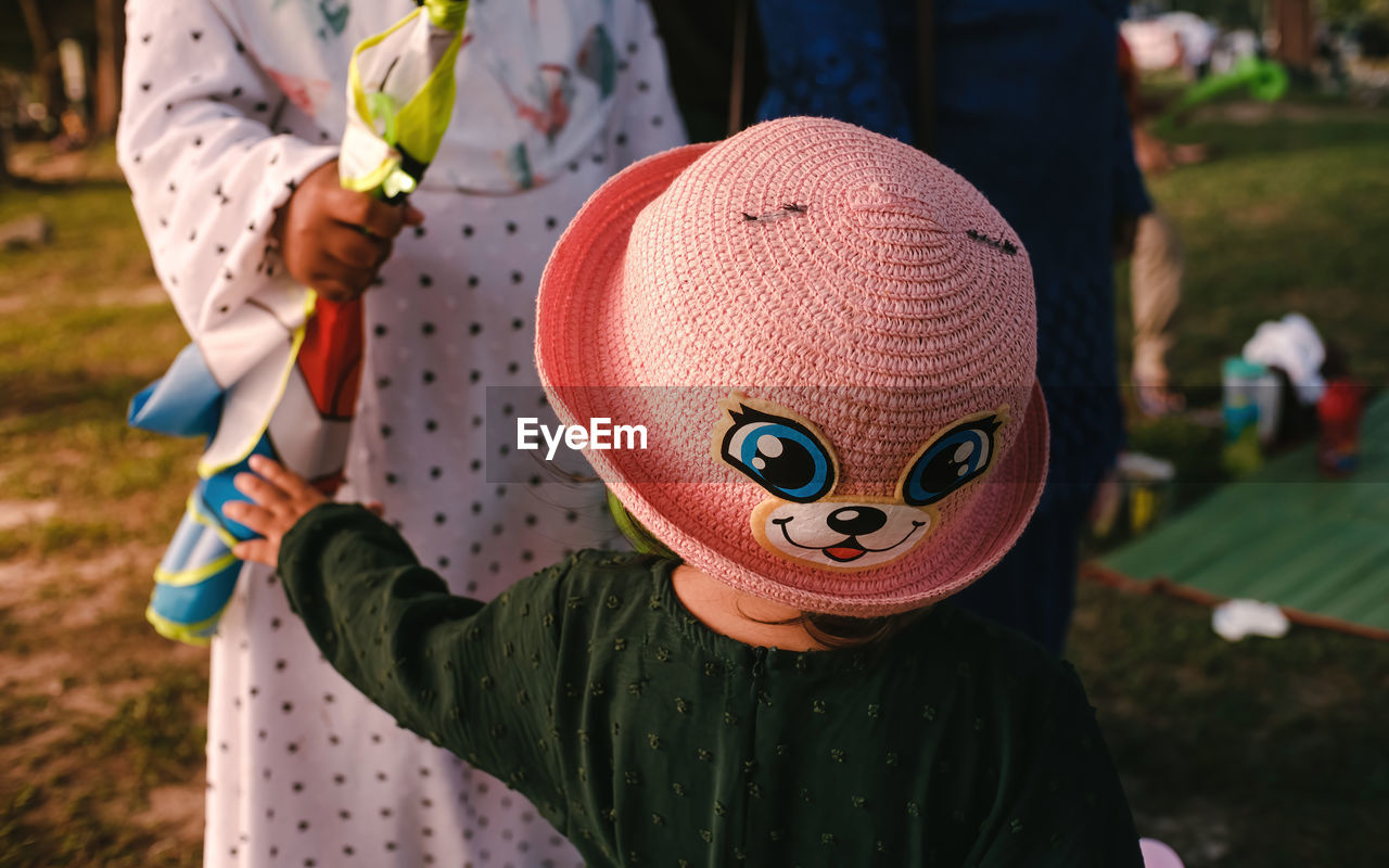 clothing, childhood, focus on foreground, one person, men, child, day, nature, spring, adult, outdoors, representation, leisure activity, costume, holding, celebration, standing, front view, person, fun, women, lifestyles, hat, toy, midsection, disguise