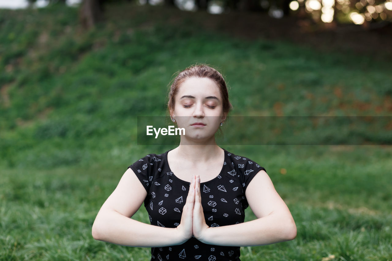 The relaxed girl is doing yoga in the park on carpet