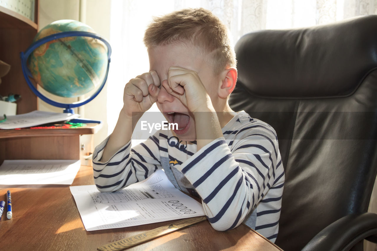 Close-up of crying child sitting at home