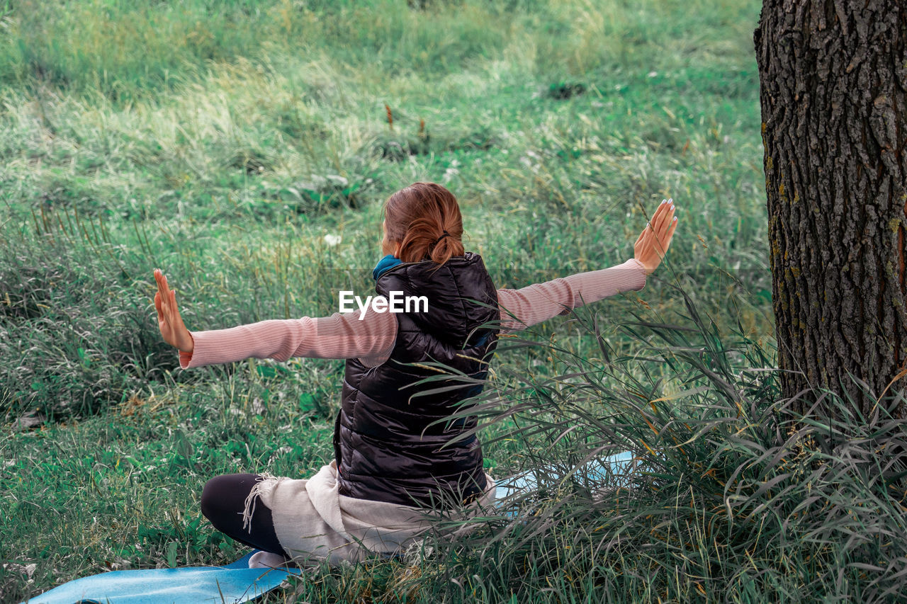 Young woman practicing yoga in the park. concept of mental health, wellness.