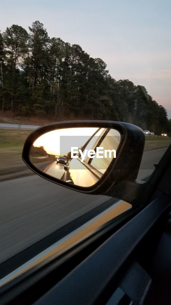 Reflection of car on side-view mirror during sunset