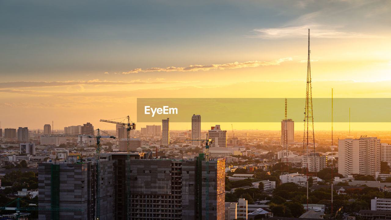 Modern buildings in city against sky during sunset