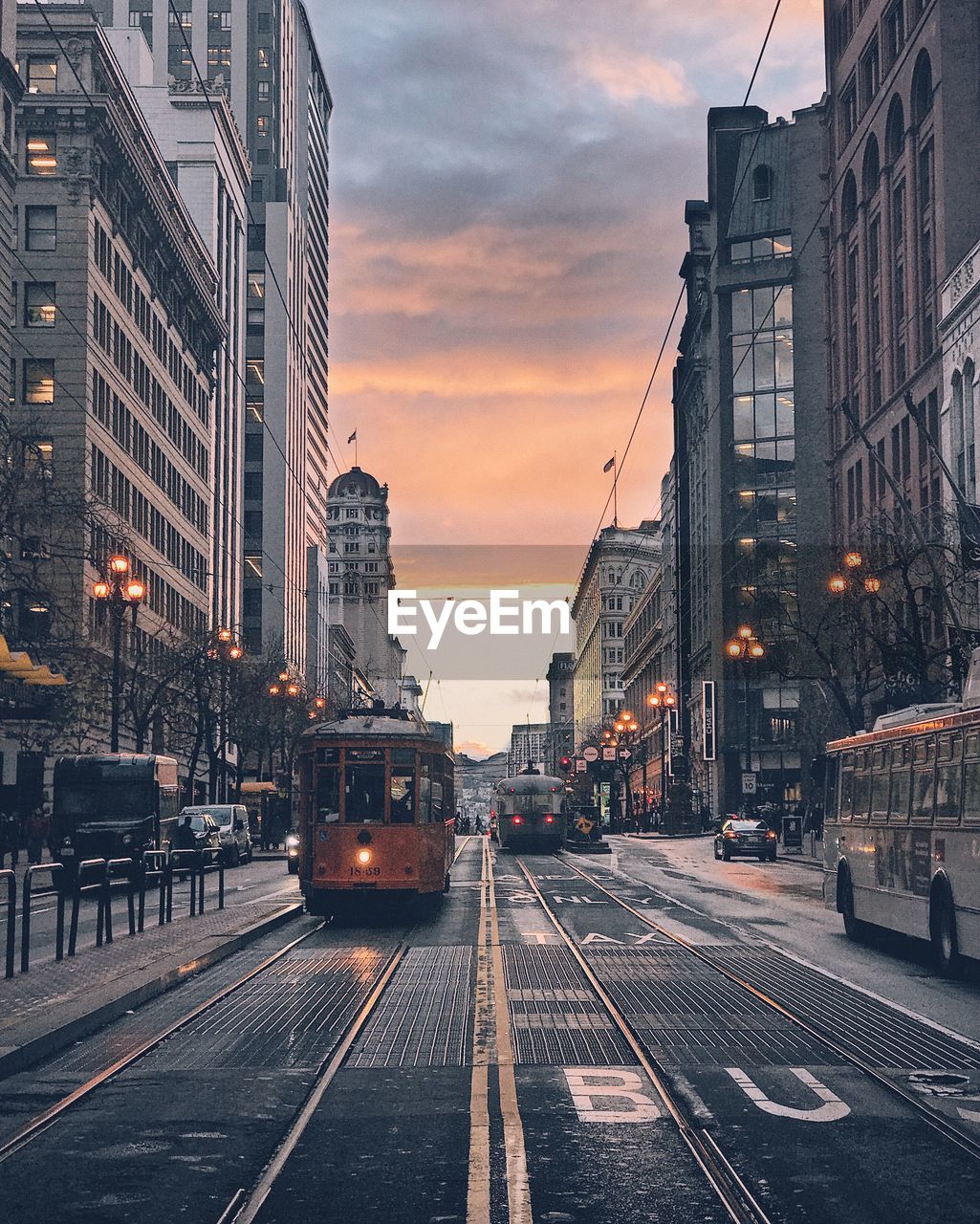 Tramway on street against cloudy sky during sunset